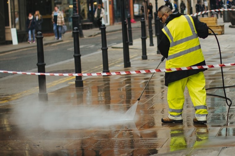 Worker pressure washing an exterior sidewalk